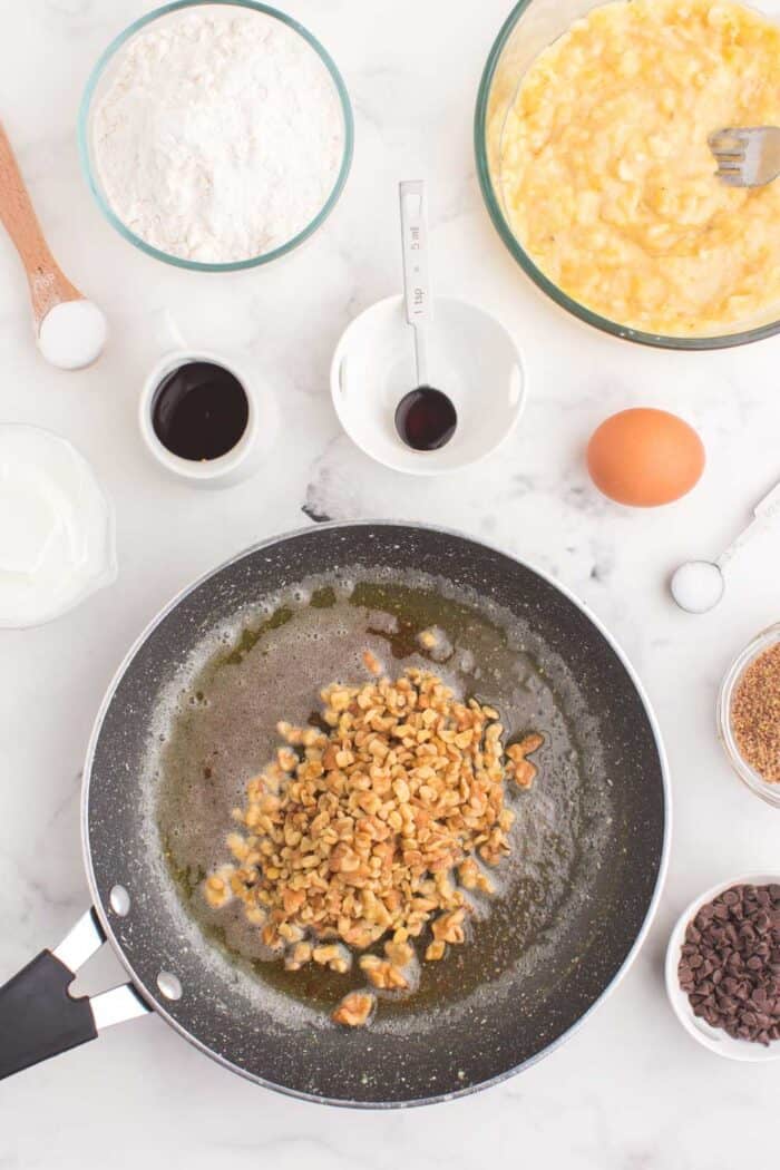 walnuts in a skillet of melted browned butter surrounded by the other muffin ingredients