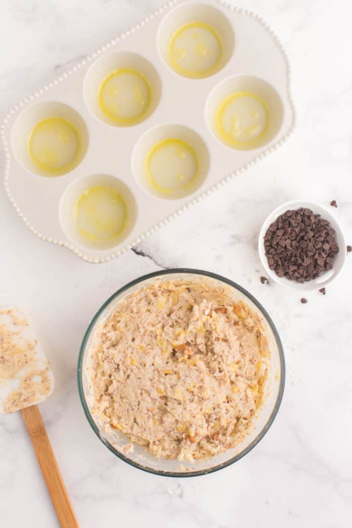 bowl of gluten free banana muffin batter with mini chocolate chips in a bowl next to it