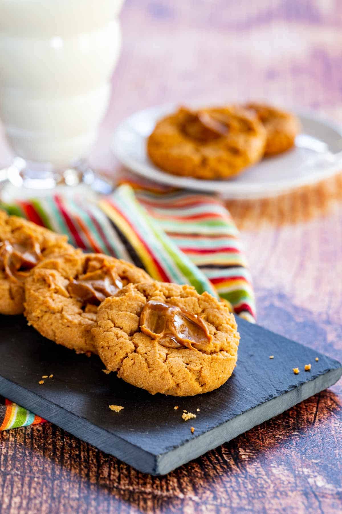 a platter and a plate with peanut butter dulce de leche thumbprints and a glass of milk