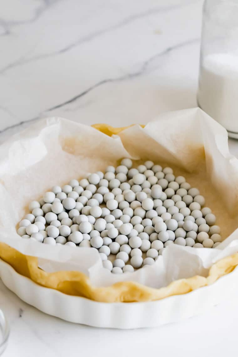A gluten-free pie crust lined with parchment paper and filled with pie weights.