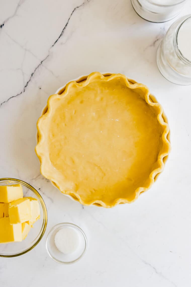 Overhead view of gluten-free pie dough pressed into a pie plate on a marble countertop.
