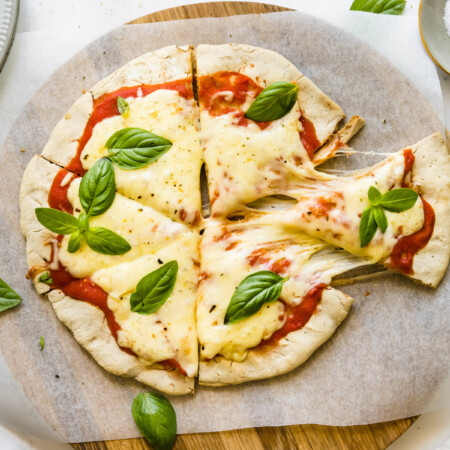 A spatula pulling one slice of gluten free pizza apart from the rest of the sliced pizza