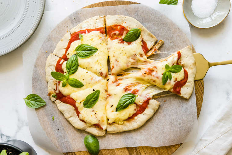 A spatula pulling one slice of gluten free pizza apart from the rest of the sliced pizza