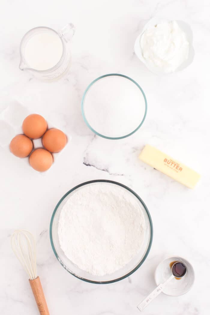 Dry ingredients after being whisked in a bowl on a tale surrounded by the remaining cake ingredients