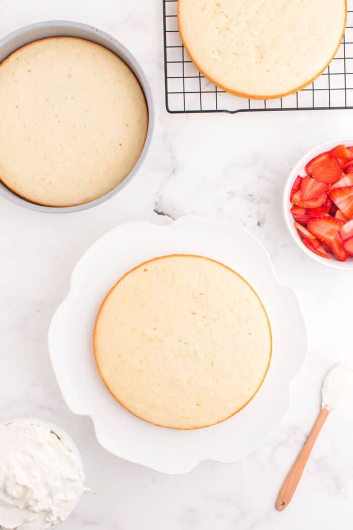 three baked cake layers with one on a cake platter