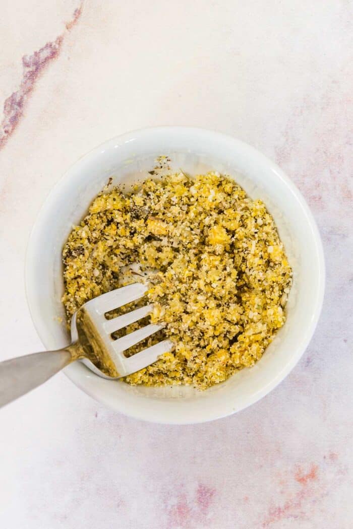 small bowl with a fork mixing a parmesan cheese and cornmeal mixture
