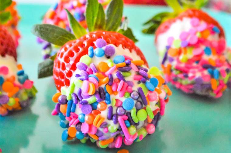 rainbow sprinkles covering a white chocolate dipped strawberry