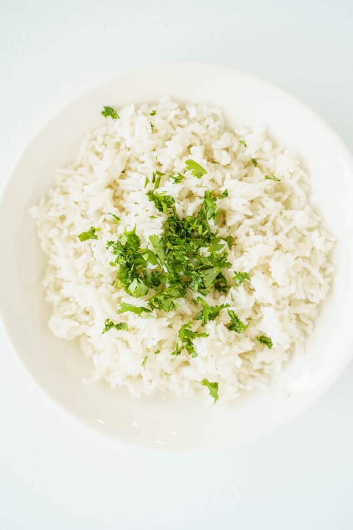 minced cilantroc on top of a bowl of white rice