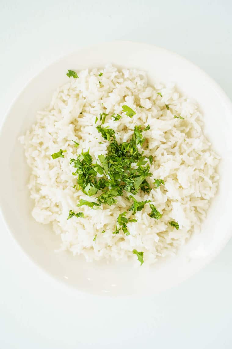 minced cilantro on top of a bowl of white rice.
