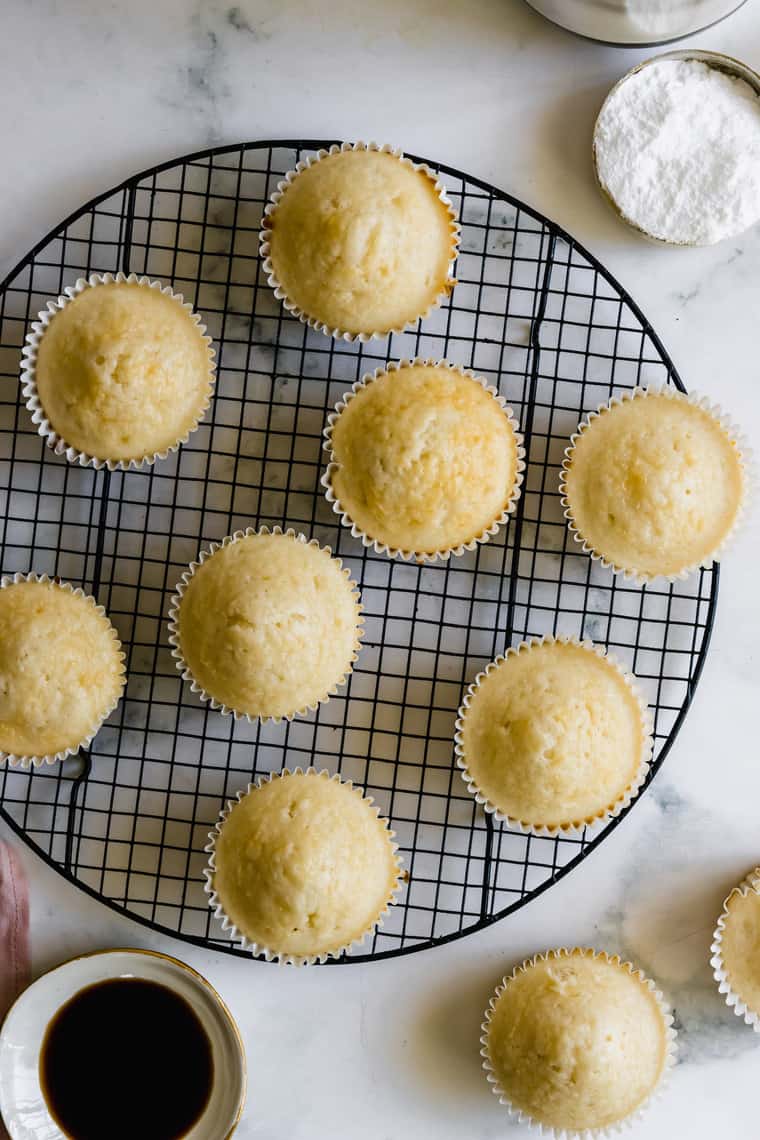 Eight Unfrosted Vanilla Cupcakes on Top of a Round Wire Rack