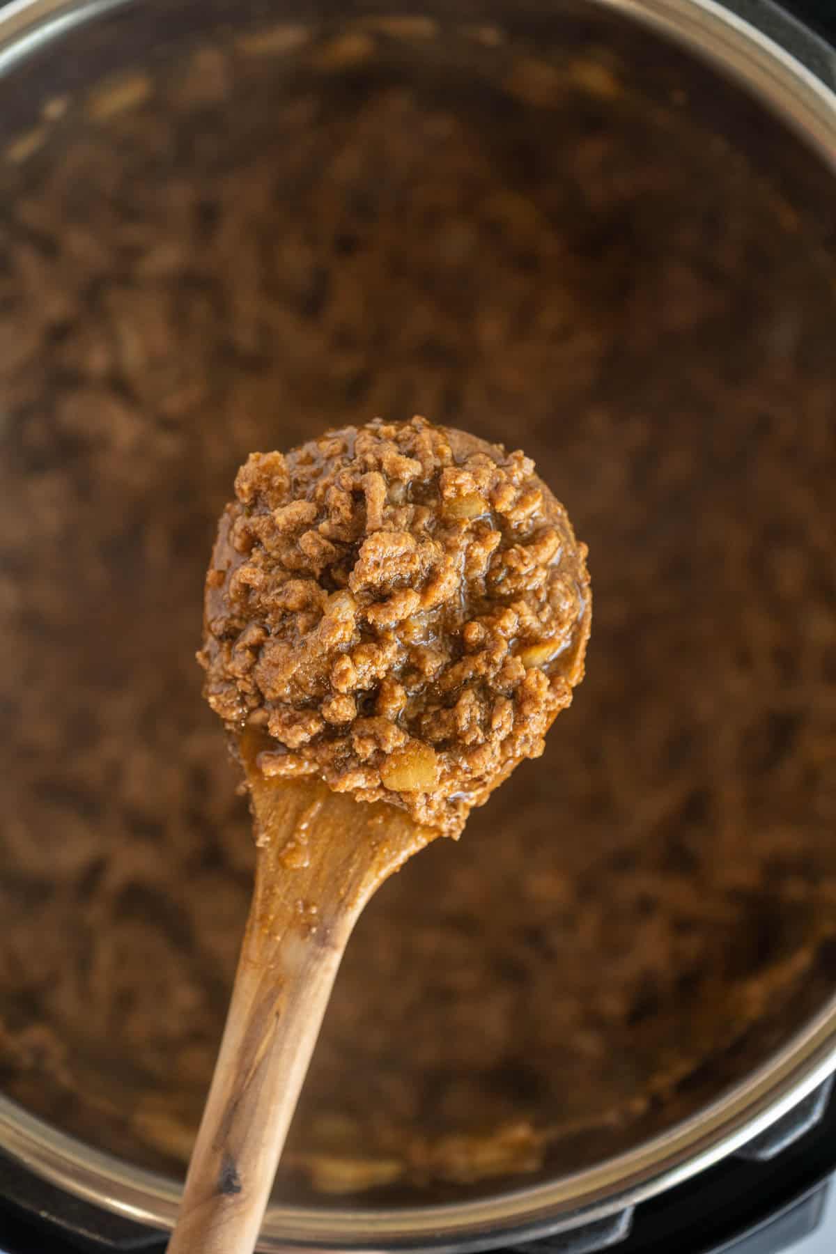 A Wooden Spoon Holding a Bite of Ground Beef Over an Instant Pot
