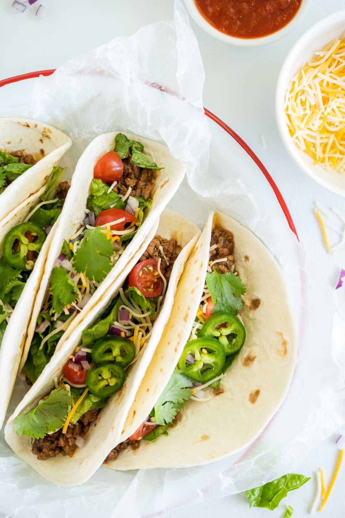 A Close-Up Shot of Four Instant Pot Ground Beef Tacos on a White Plate with a Red Rim