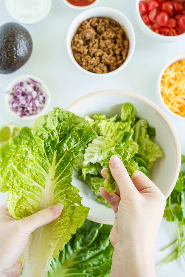 A Hand Ripping Apart a Lettuce Leaf for the Deconstructed Taco