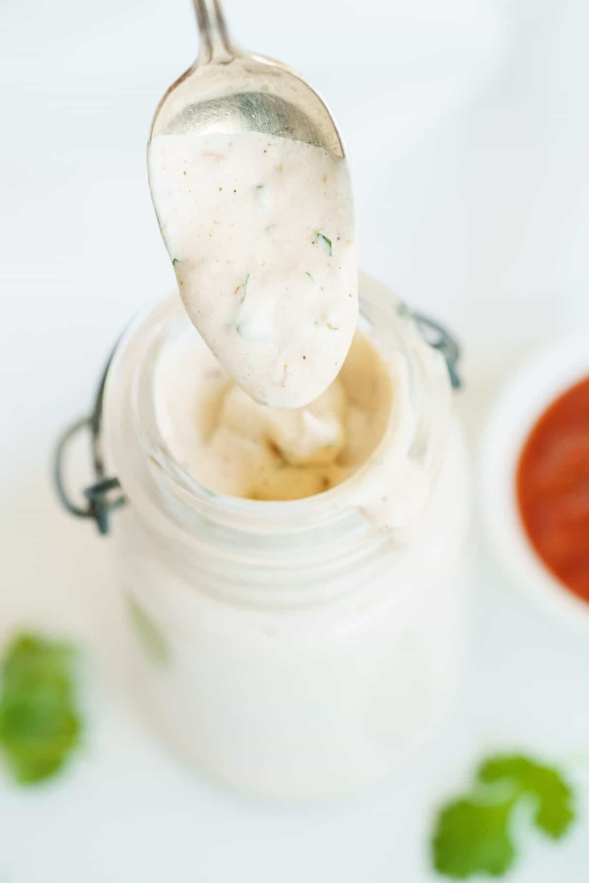 A Spoon Scooping Up Some Salad Dressing From a Glass Jar