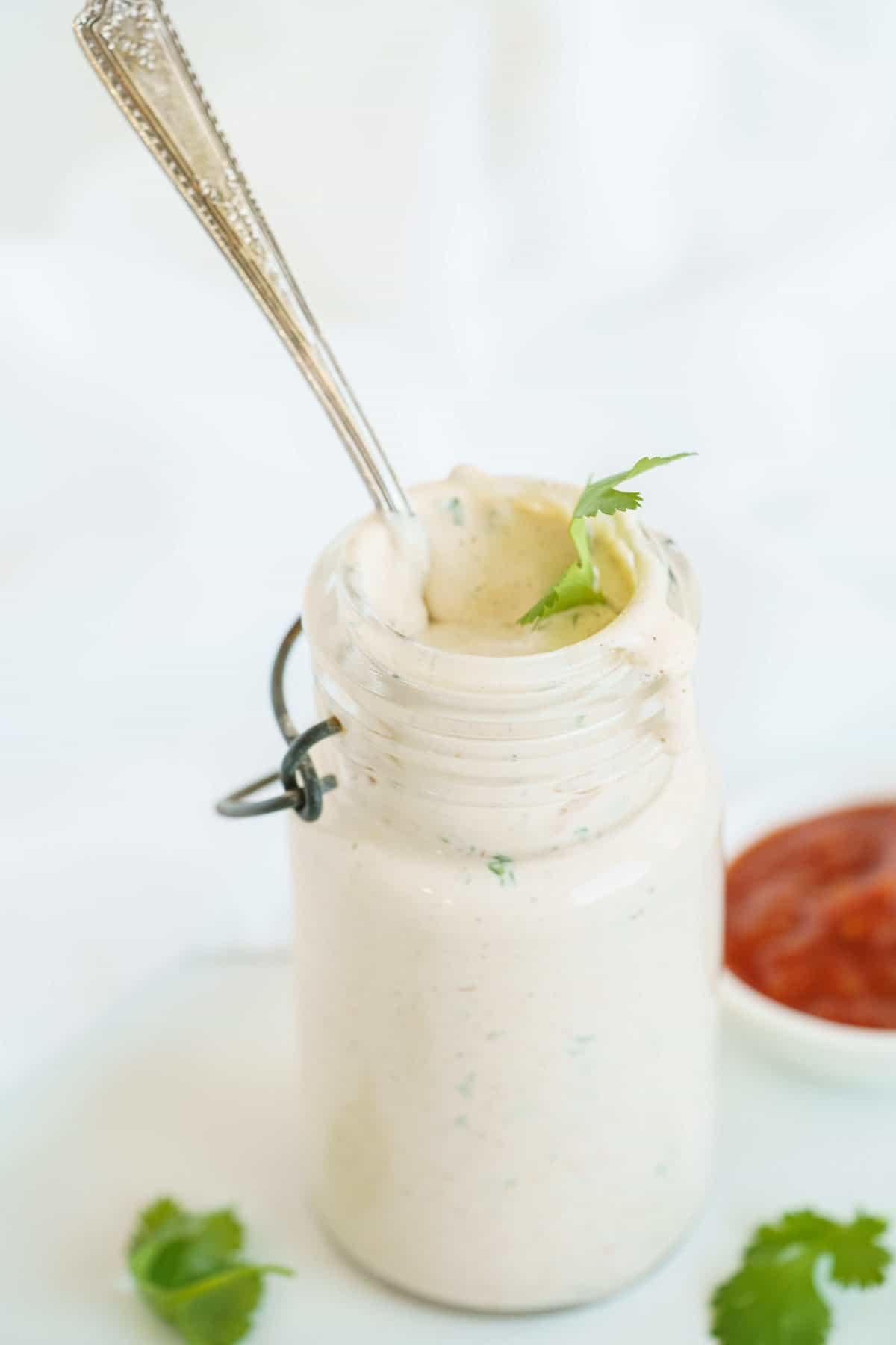 A Glass Container of Creamy Dressing with a Long Spoon Sticking Out
