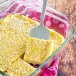 baked polenta cut into squares in a baking dish with one lifted with a serving spatula