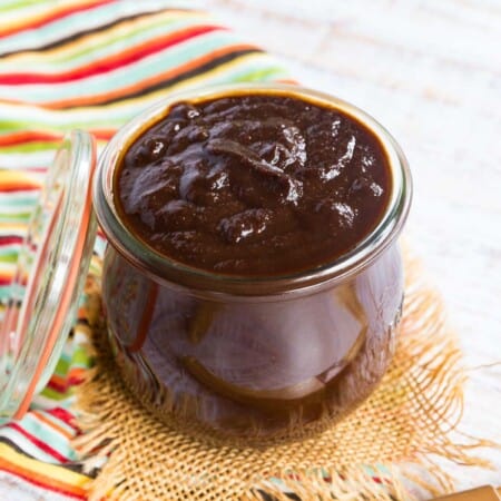 glass jelly jar filled with barbecue sauce on a striped napkin