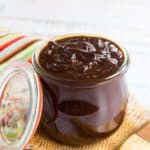 glass jar of bbq sauce with a lid leaning aganist it