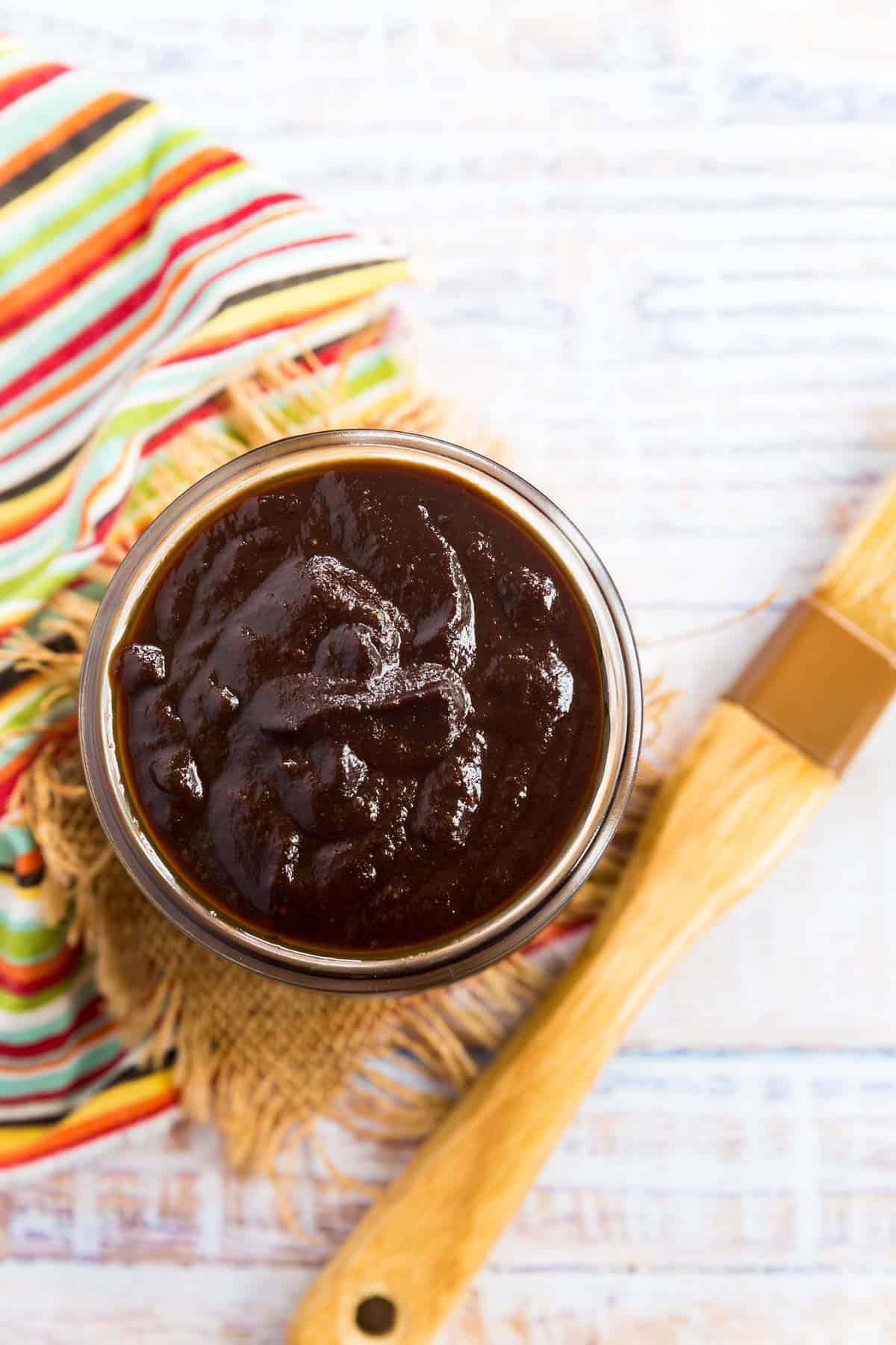 top of a jar of homemade barbeque sauce with a brush laying next to it