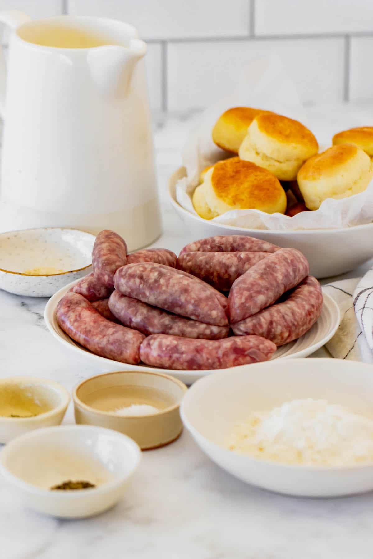 A Plate of Sausage, a Bowl of Biscuits and the Rest of the Ingredients on a Countertop