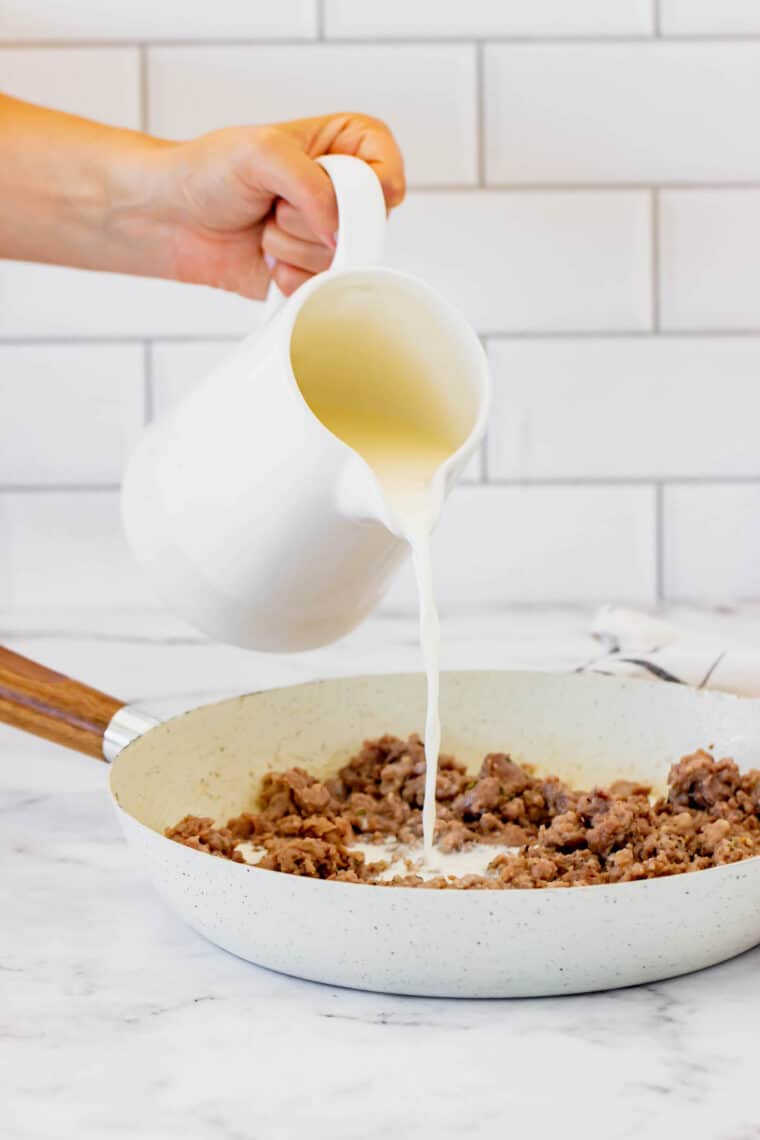 Milk Being Poured Into a Skillet Filled with Sausage and Spices