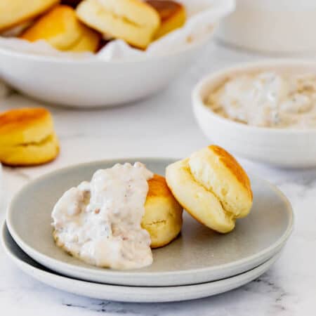 Two Stacked Plates Holding a Helping of Biscuits and Gravy