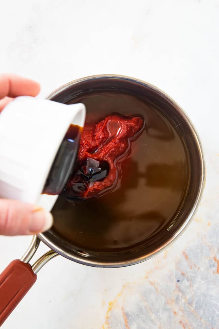 pouring molasses into the pot with other barbecue sauce ingredients