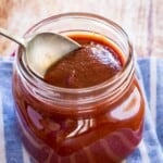spoon scooping bourbon bbq sauce out of a glass jar