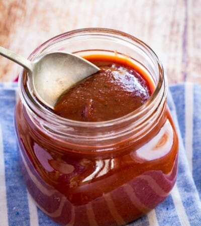 spoon scooping bourbon bbq sauce out of a glass jar