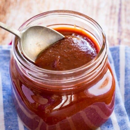 spoon scooping bourbon bbq sauce out of a glass jar