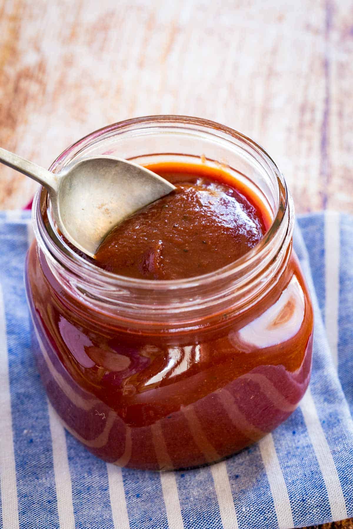 spoon scooping bourbon bbq sauce out of a glass jar