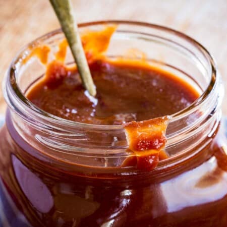 a bit of sauce dripping over the edge of a glass jar full or bourbon barbecue sauce