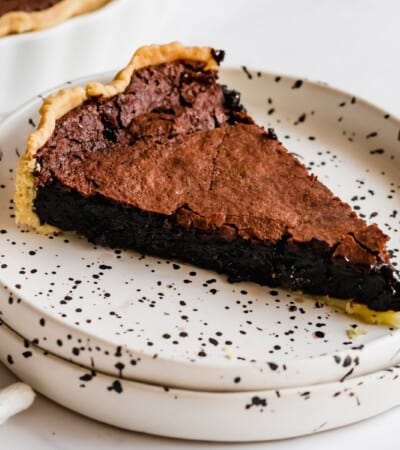 slice of gluten free chocolate chess pie on a white plate with black speckles