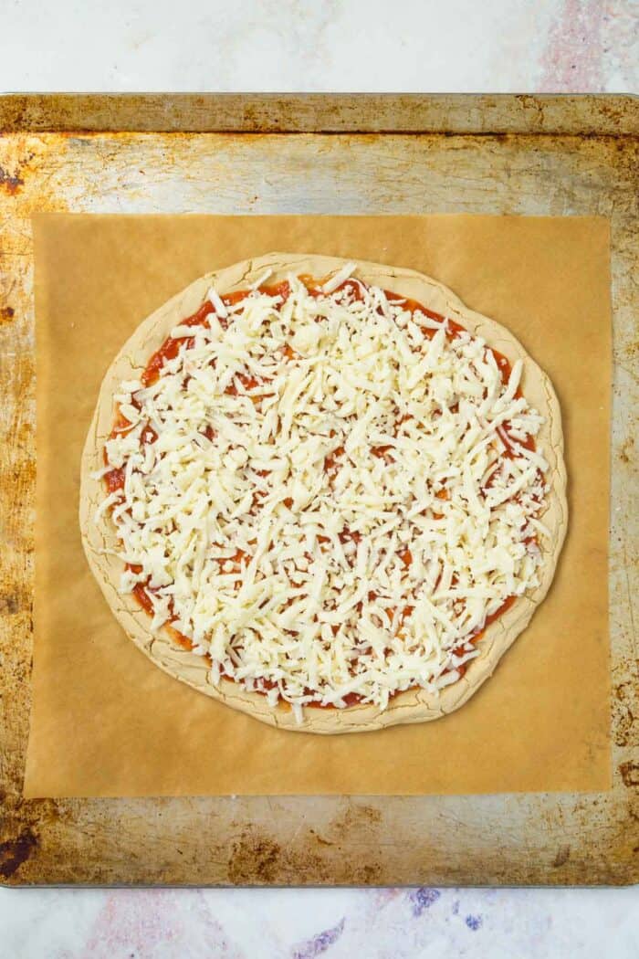 pizza crust with tomato sauce and mozzarella cheese on a baking sheet