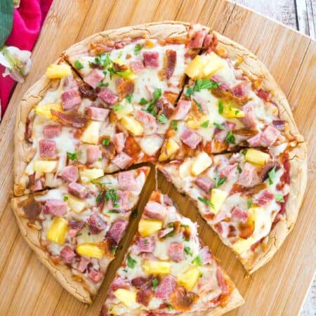 sliced hawaiian pizza with a spatula pulling on slice away