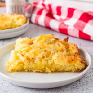 square piece of hashbrown casserole with pepper on top on a white plate