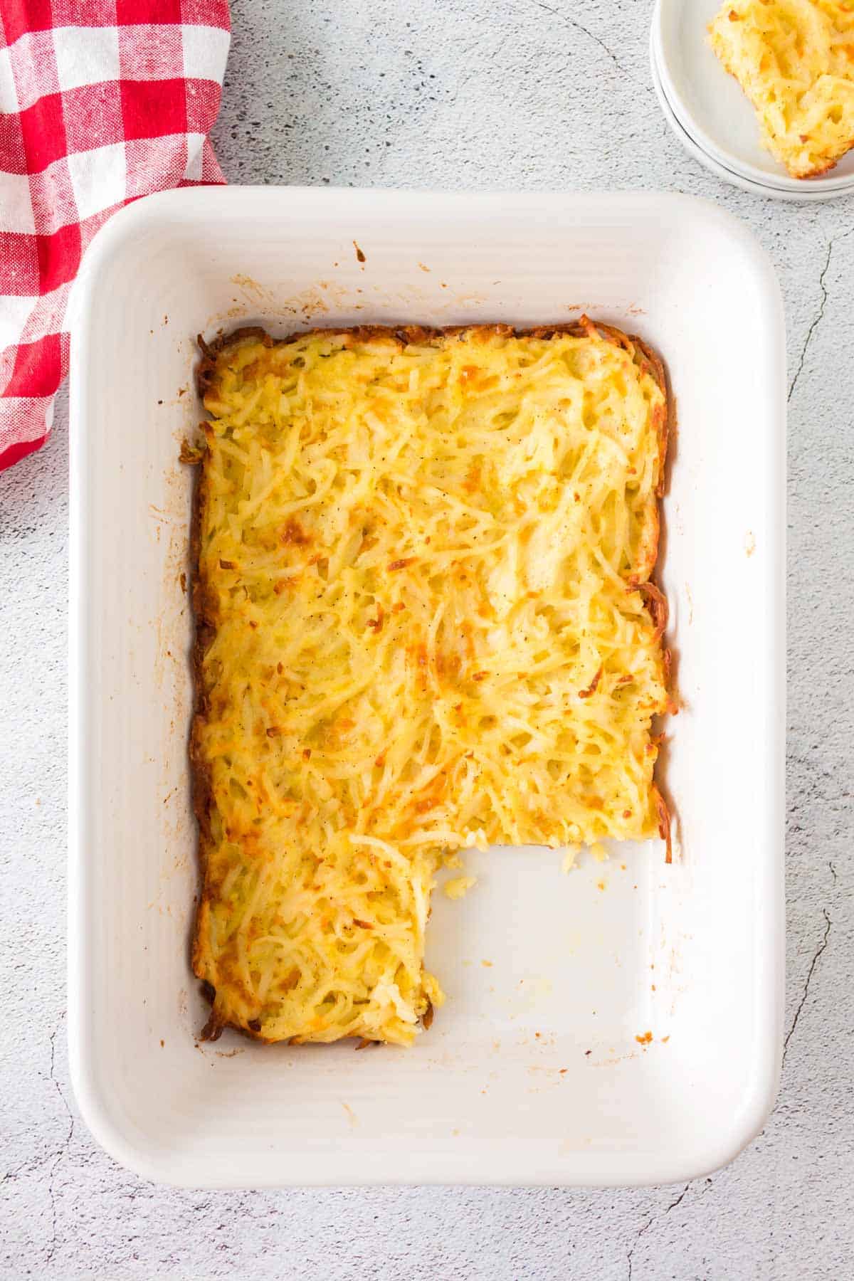 hashbrown potato casserole in the baking dish with a square removed and on a small plate