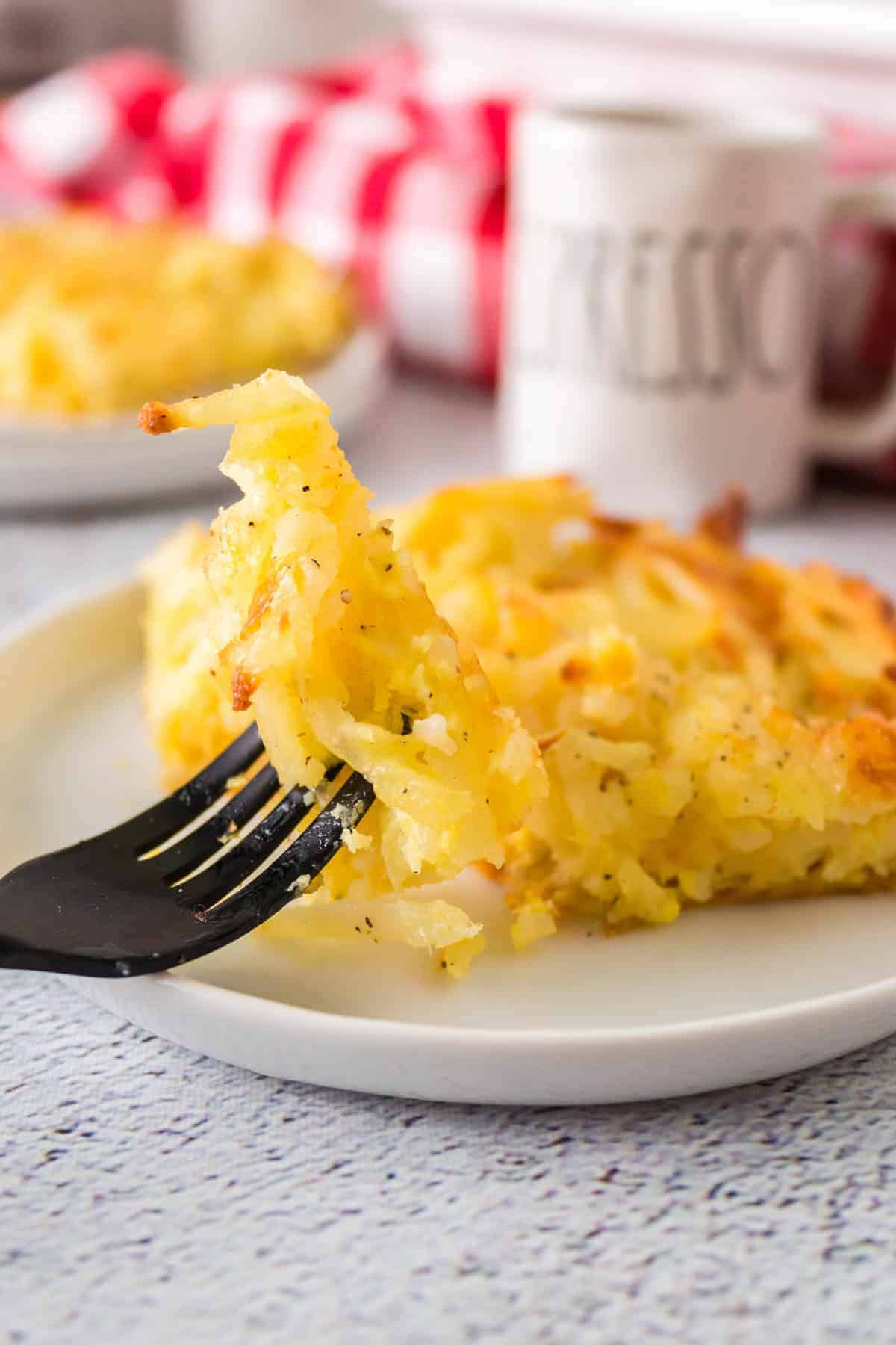 fork picking up a piece of the potato casserole on a plate