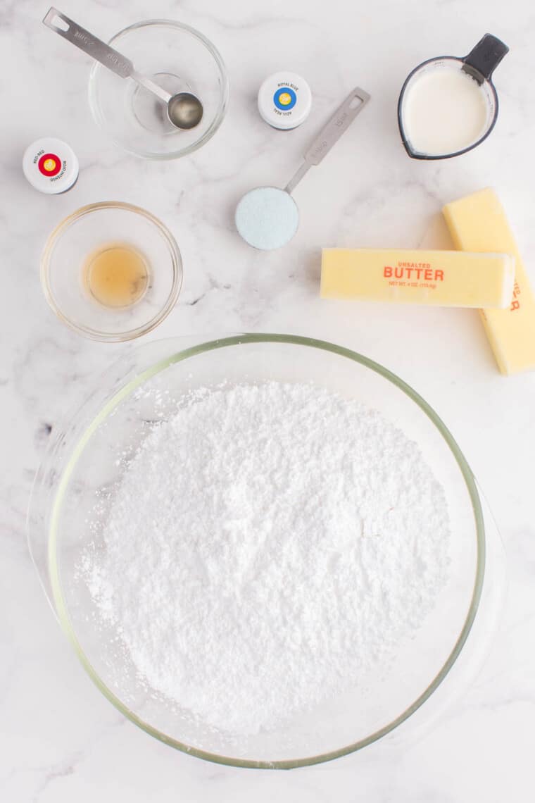 powdered sugar, butter, heavy cream, and ingredients to color and flavor the red, white, and blue buttercream on a marble table