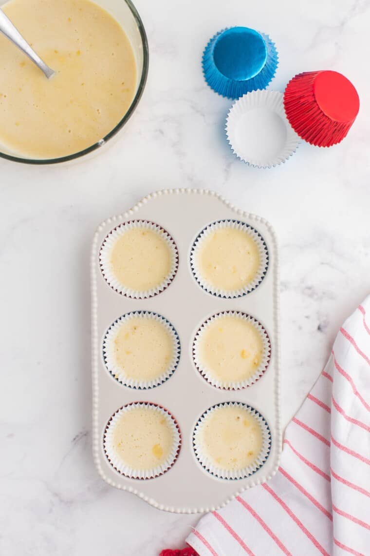 cupcake pan with liners filled with batter and a bowl of more batter