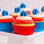 several cupcakes in red foil and blue foil wrappers with layers of red, white, and blue frosting