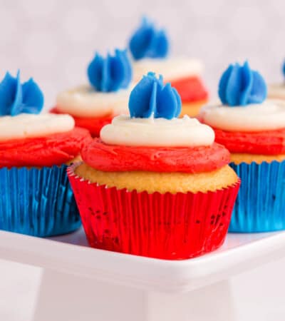 several cupcakes in red foil and blue foil wrappers with layers of red, white, and blue frosting
