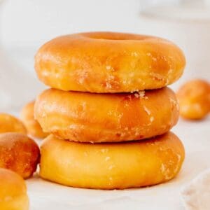 three stacked glazed donuts surrounded by donut holes