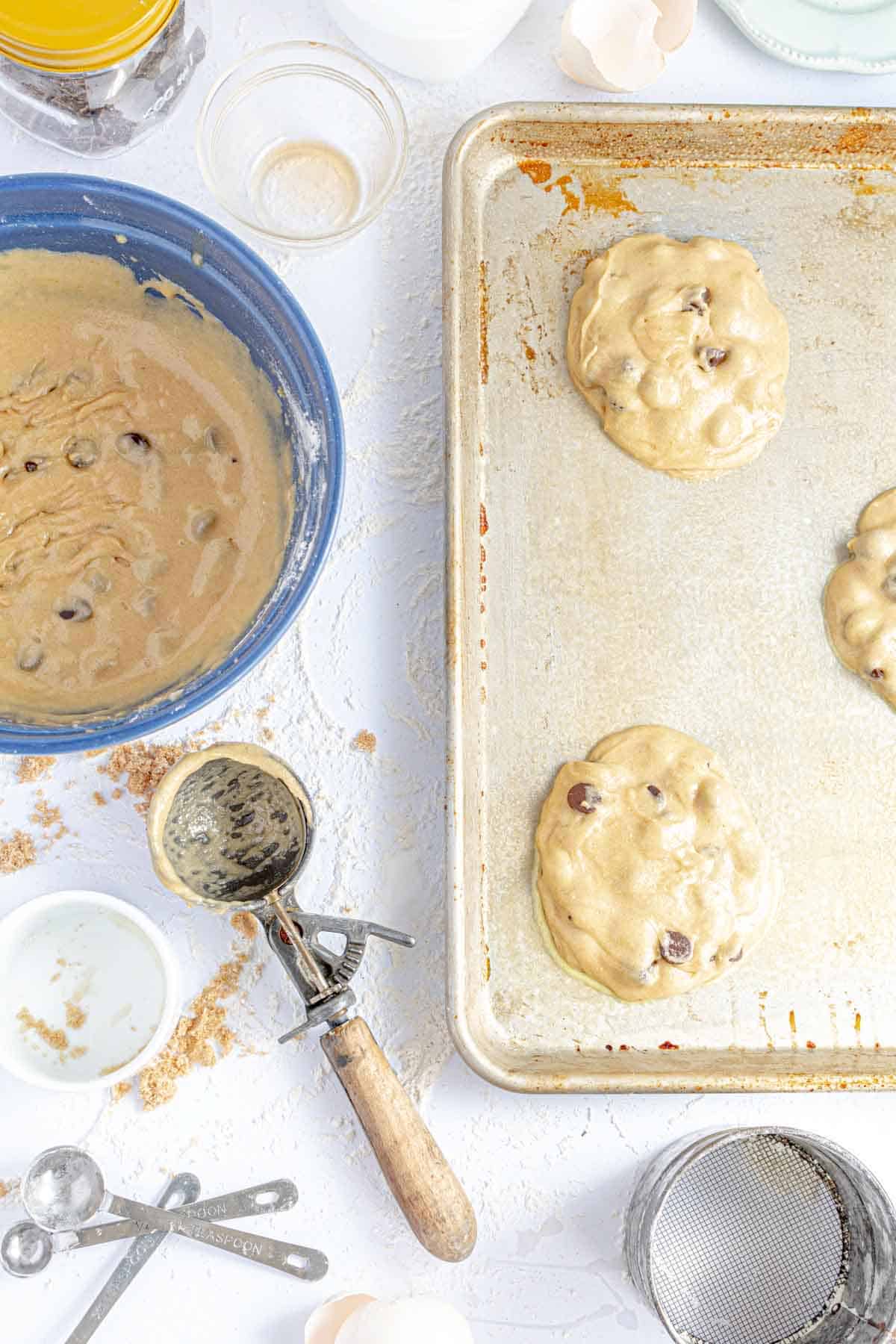 Raw Gluten-Free Cookie Dough on a Greased Baking Pan Beside an Ice Cream Scoop