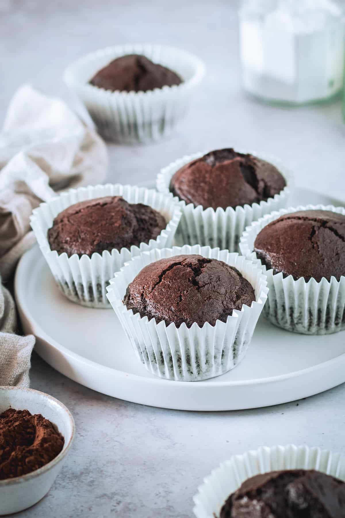 Four Lined, Unfrosted Chocolate Cupcakes on a Round Plate