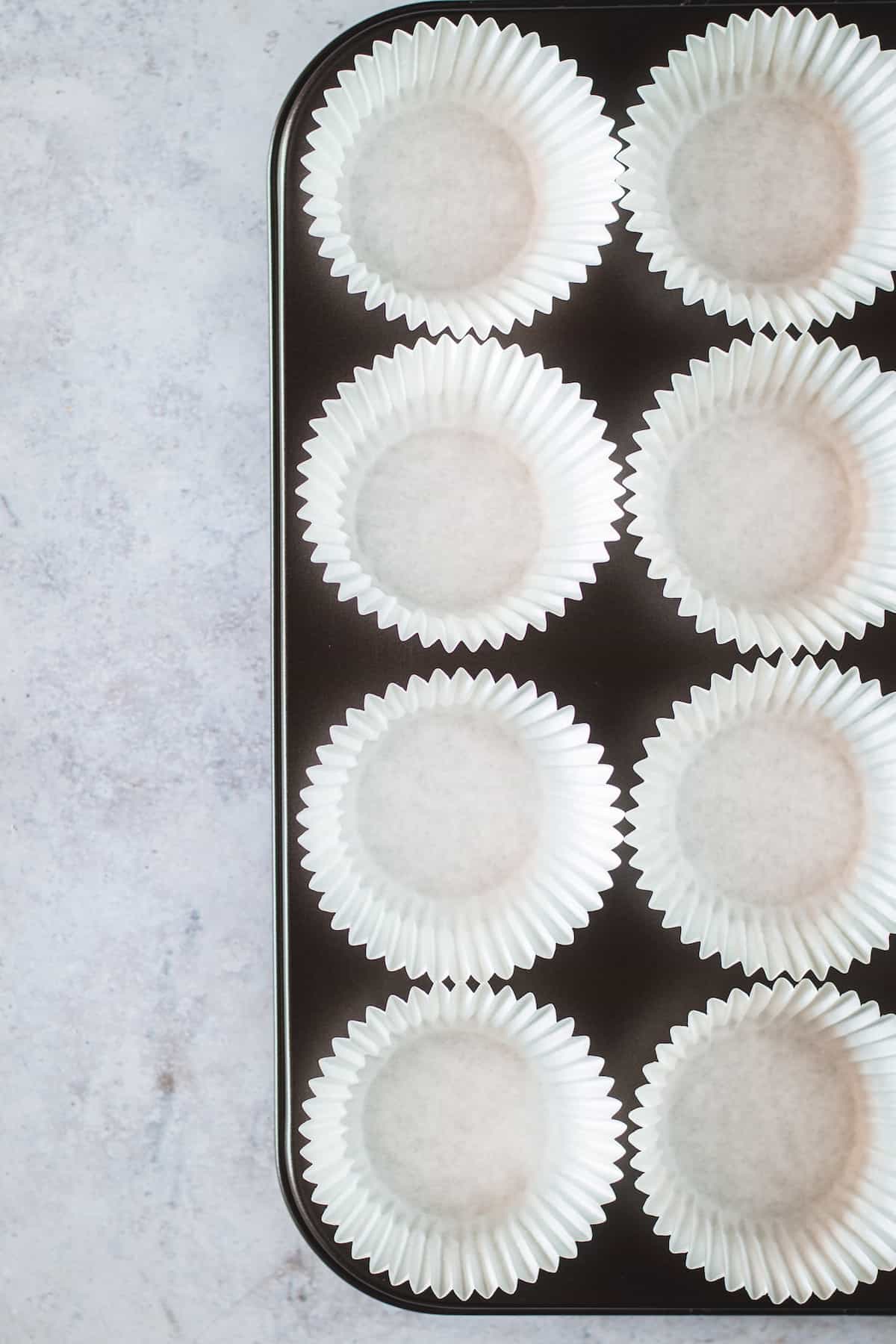 Eight White, Unfilled Cupcake Liners Inside a Metal Cupcake Pan