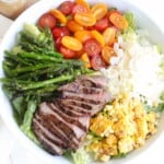 white bowl filled with a grilled steak salad with corn, asparagus, tomatoes, and shaved parmesan