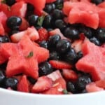 full bowl of fruit salad with berries and watermelon stars in a honey lime dressing