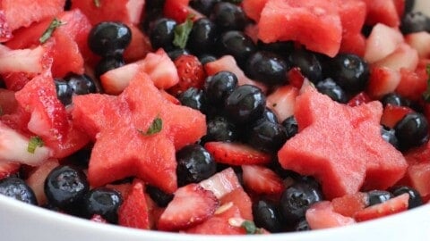 full bowl of fruit salad with berries and watermelon stars in a honey lime dressing