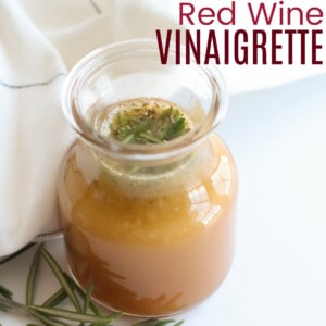 bottle of red wine vinegar salad dressing next to a white napkin and a prig of fresh rosemary
